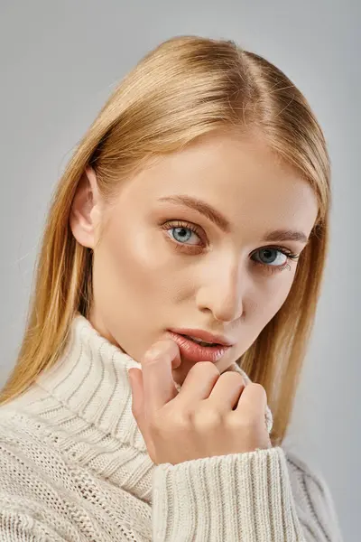 Portrait rapproché de jeune blonde en pull d'hiver aux cheveux blonds et maquillage naturel sur gris — Photo de stock