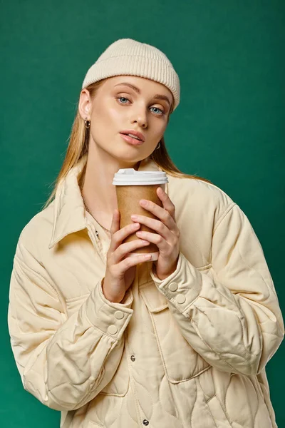 Affascinante donna in berretto cappello e giacca calda ed elegante con caffè per andare su verde, emozioni invernali — Foto stock