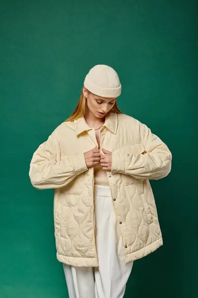 Модна жінка в капелюсі Бані теплий куртка зі слонової кістки на зеленому тлі, зимова вулична мода — стокове фото