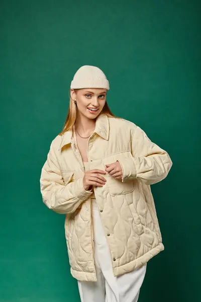 Donna sorridente in giacca calda e cappello alla moda beanie guardando la fotocamera verde, tendenza della moda invernale — Foto stock