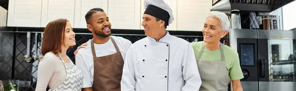 Jolly diverse students smiling at mature joyous chef during cooking lesson, confectionery, banner — Stock Photo