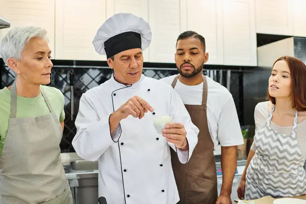 Good looking mature chef discussing with his multiracial students how to bake, confectionary — Stock Photo