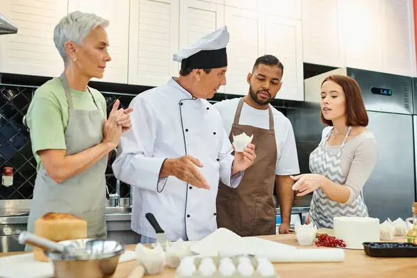 Buono chef maturo cercando spiegando materiali ai suoi studenti multirazziali sulla lezione di cucina — Foto stock