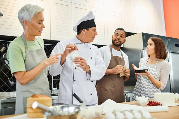 Diverse people in casual attires with aprons listening to mature chef attentively, cooking courses — Stock Photo