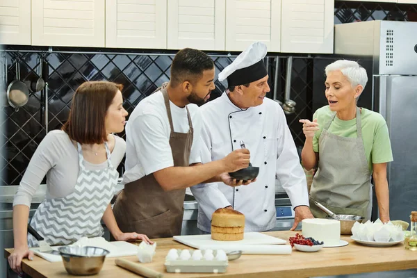 Young diverse friends and chef looking at mature woman in apron asking question, cooking courses — Stock Photo