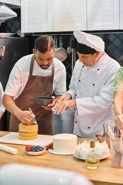 Maturo chef in cappello bianco insegnare al suo studente afroamericano come utilizzare pennello in silicone sulla torta — Foto stock