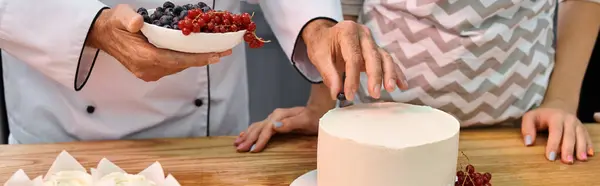 Chef mature montrant à une jeune femme comment décorer un gâteau avec des baies, des cours de cuisine, une bannière — Photo de stock