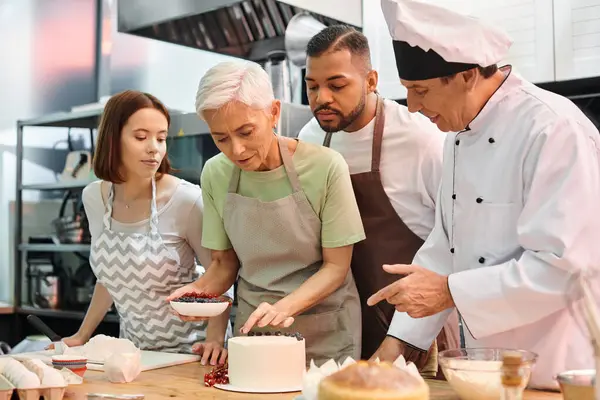 Handsome mature chef explaining to his multicultural students how to decorate cake, cooking courses — Stock Photo