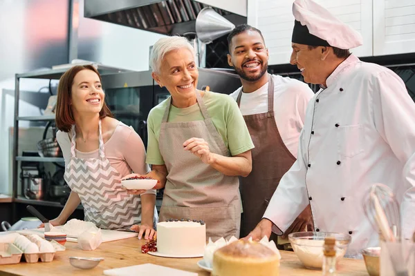 Joyous multiracial students smiling at chef while decorating delicious cake, cooking courses — Stock Photo