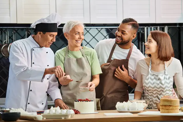 Lustige reifen Koch hilft seinen gemischtrassigen glücklichen Studenten, köstlichen Kuchen zu dekorieren, Kochkurse — Stockfoto