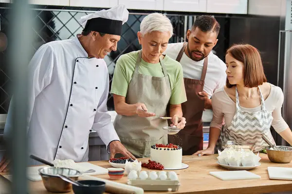 Femme mature décoration gâteau à côté de ses amis et chef interracial joyeux, cours de cuisine — Photo de stock