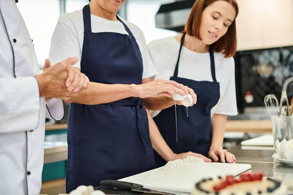 Abgeschnittene Ansicht einer reiferen Köchin beim Eierbrechen neben ihrer jungen Kollegin und Chefköchin — Stockfoto