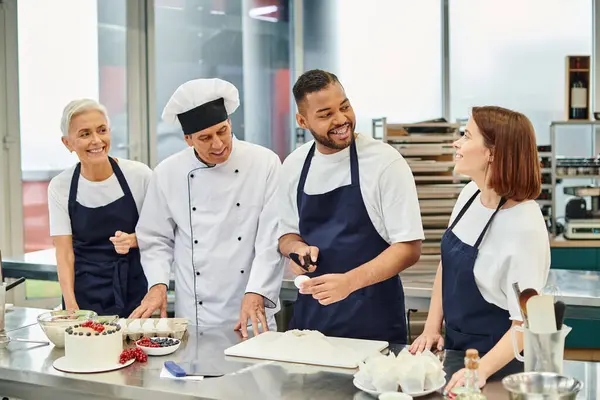 Joyous african american male chef breaking egg and smiling happily at his colleagues and chief cook — Stock Photo