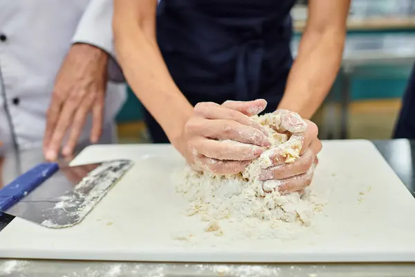 Vista cortada de chef feminino maduro trabalhando com massa, enquanto cozinheiro chefe ajudá-la, confeitaria — Fotografia de Stock