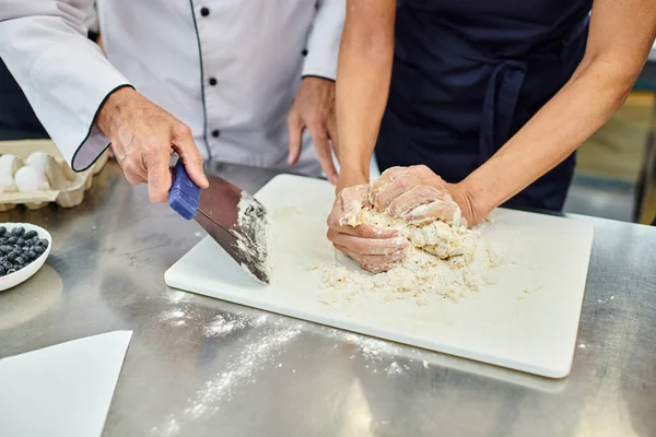 Vista ritagliata di donna matura che lavora con pasta con capo cuoco aiutandola, pasticceria — Foto stock