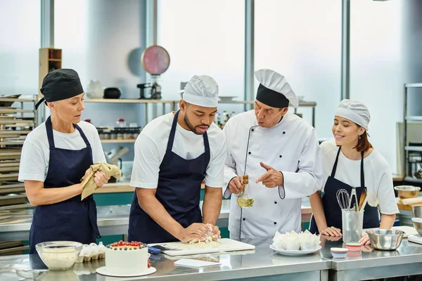 Good looking african american chef working with dough next to his colleagues and chief cook — Stock Photo