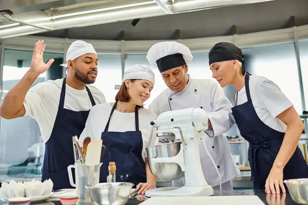 Jolly multicultural chefs watching their chief cook showing them how to use mixer, confectionery — Stock Photo