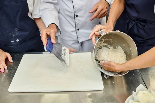 Vue recadrée du chef cuisinier mature montrant à ses cuisinières comment travailler avec de la pâte, confiserie — Photo de stock