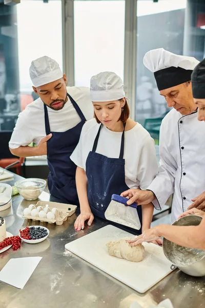 Cozinheiro chefe maduro mostrando seus diversos chefs como trabalhar com massa corretamente, confeitaria — Fotografia de Stock