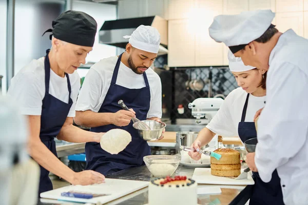 Hard working multicultural chefs and chief cook working pasty together in kitchen, confectionery — Stock Photo