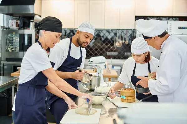 Chef di bell'aspetto in grembiuli e toques che lavorano insieme al capo cuoco su pasticceria, dolciumi — Foto stock
