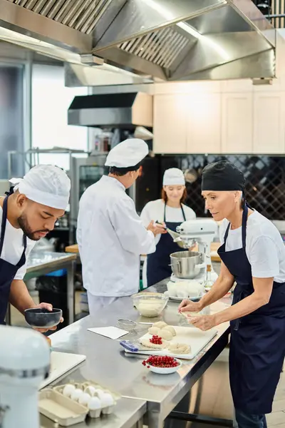 Se centran en diversos chefs en delantales que trabajan en pastelería junto a su colega borroso y cocinero jefe - foto de stock
