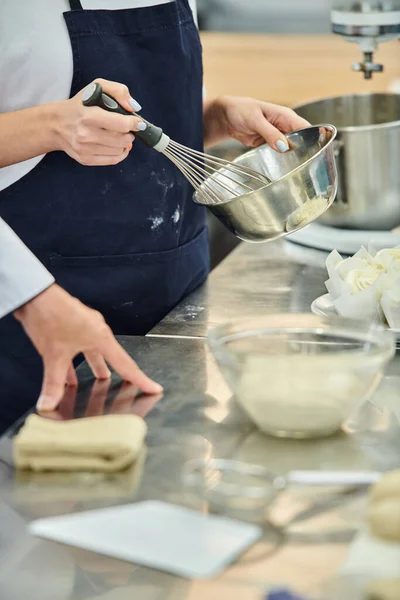 Vista ritagliata di giovane chef donna in grembiule sbattere gli ingredienti per la pasta accanto al capo cuoco — Foto stock