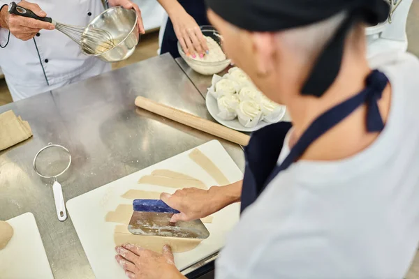 Vista cortada de chef maduro usando placa de corte na cozinha ao lado de seu colega e cozinheiro chefe — Stock Photo