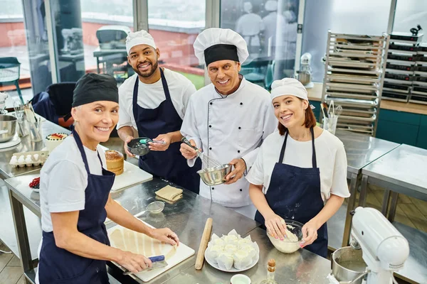 Belle équipe joyeuse et diversifiée de chefs posant avec leur chef cuisinier et souriant à la caméra — Photo de stock