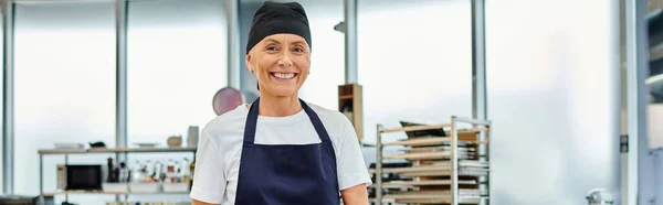 Cheerful attractive woman working with dough and smiling happily at camera, confectionery, banner — Stock Photo
