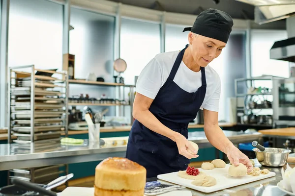 Attrayant mature femme en toque bleue et tablier travailler dur avec sa pâte, confiserie — Photo de stock