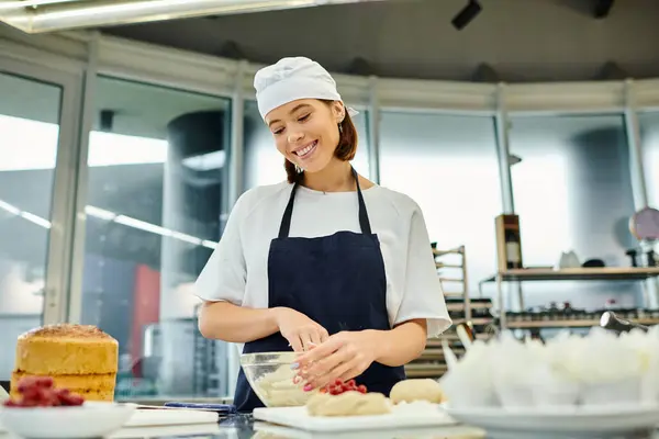 Bom olhar alegre jovem chef em toque e avental trabalhando atentamente com massa, confeitaria — Fotografia de Stock