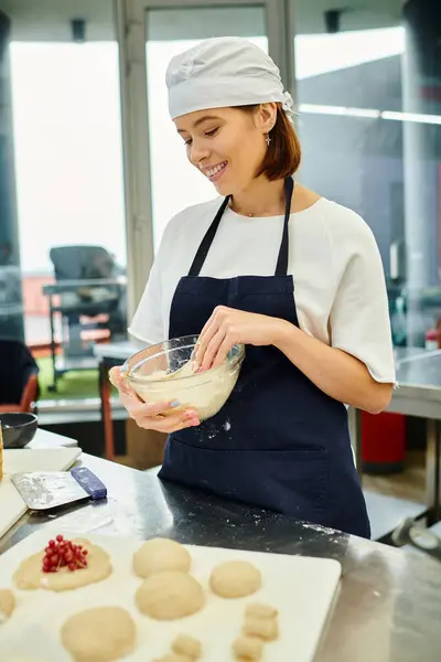 Cheerful young beautiful female chef in blue toque and apron working with dough, confectionery — Stock Photo