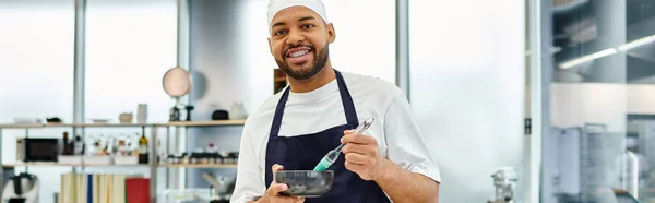 Bello jolly chef americano africano in grembiule con pennello in silicone e sorridente alla macchina fotografica, banner — Foto stock