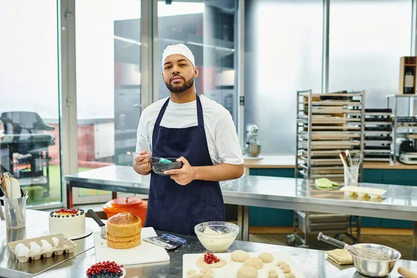 Добре виглядає афроамериканський шеф-кухар в блакитному кольорі і фартух, що працює на тісті і дивиться на камеру — стокове фото
