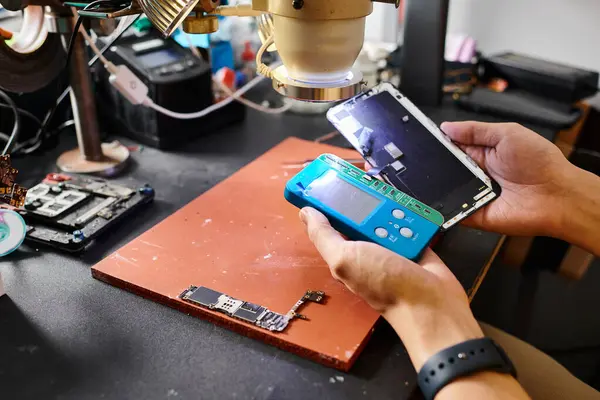 Cropped view of technician working with smartphone and voltmeter in repair shop, small business — Stock Photo