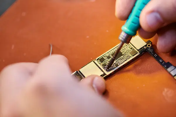 Close up view of cropped technician assembling chipset by soldering in repair shop, small business — Stock Photo