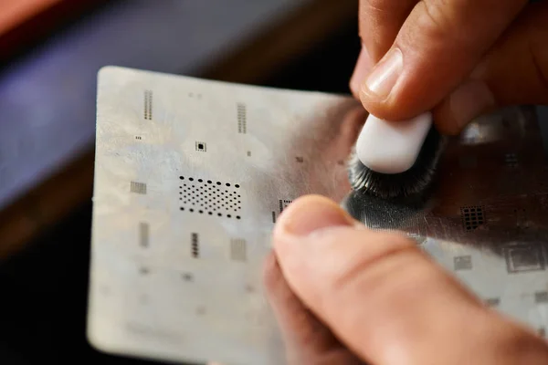 Vue rapprochée de technicien qualifié nettoyage microschéma avec brosse tout en travaillant en atelier — Photo de stock