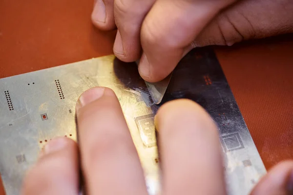 Cropped view of technician scratching chipset during diagnostics in workshop, small business — Stock Photo