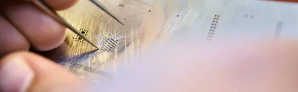 Частковий вид досвідченого техніка з пінцетом біля електронного чіпсету в майстерні, банер — стокове фото