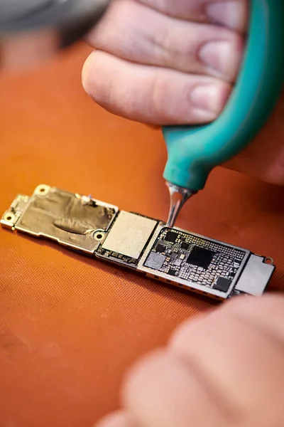 Teilansicht des Reparateurs, der elektronisches Mikroschema reinigt, während er in einer privaten Werkstatt arbeitet — Stockfoto