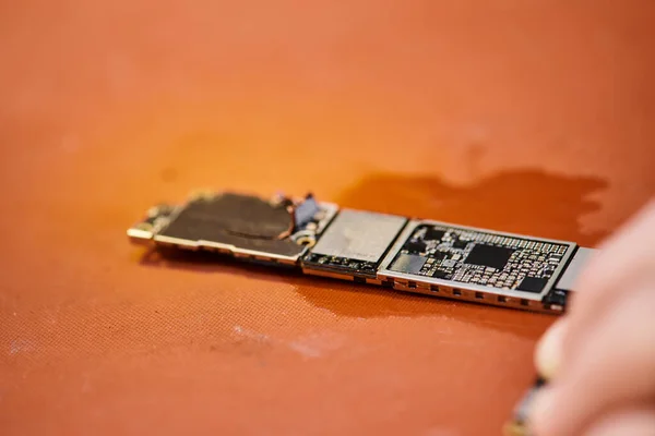 Microschéma de dispositif électronique près de technicien cultivé sur la table en atelier, petite entreprise de réparation — Photo de stock