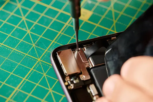 Ausgeschnittene Ansicht des Technikers beim Öffnen des Mobiltelefons mit dem Schraubenzieher während des Tests in der eigenen Werkstatt — Stockfoto
