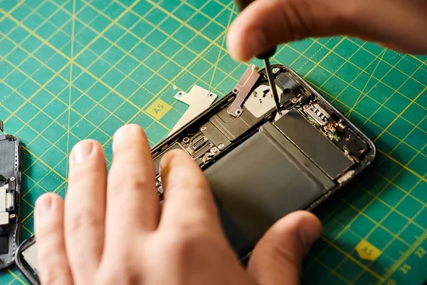 Abgeschnittene Ansicht eines Technikers, der Smartphone testet, während er in einer privaten Werkstatt arbeitet, Kleinunternehmen — Stockfoto