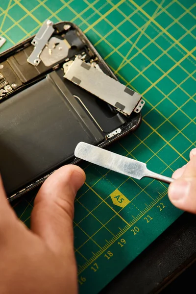 Vista ritagliata del riparatore smartphone di apertura durante i test in officina, piccola impresa privata — Foto stock