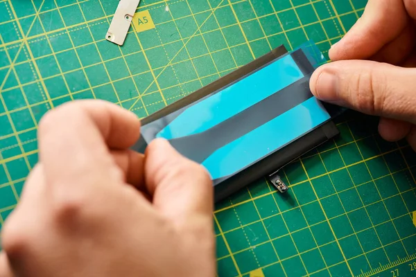 Обрезанный вид профессионального ремонтника тестирования батареи мобильного телефона в мастерской, малый бизнес — стоковое фото