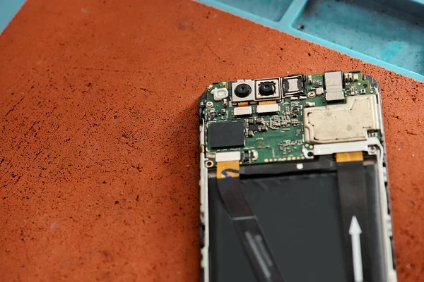 Blick von oben auf zerlegtes kaputtes Handy auf dem Tisch in moderner Werkstatt, Reparaturbetrieb — Stockfoto