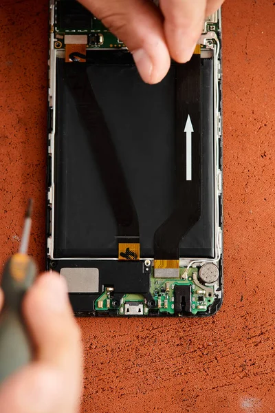 Vue recadrée du réparateur qualifié retirant la batterie du téléphone portable dans l'atelier, petite entreprise — Photo de stock
