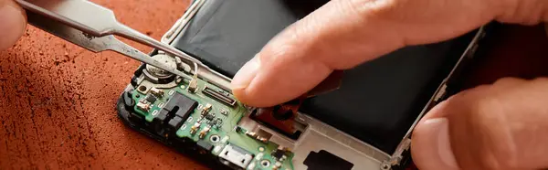 Cropped view of skilled technician disconnecting battery of smartphone with tweezers, banner — Stock Photo