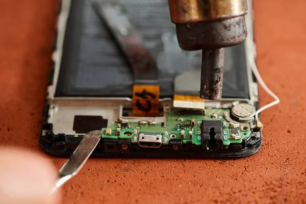 Vista ritagliata di esperto riparatore smontaggio telefono cellulare durante la manutenzione in officina — Foto stock